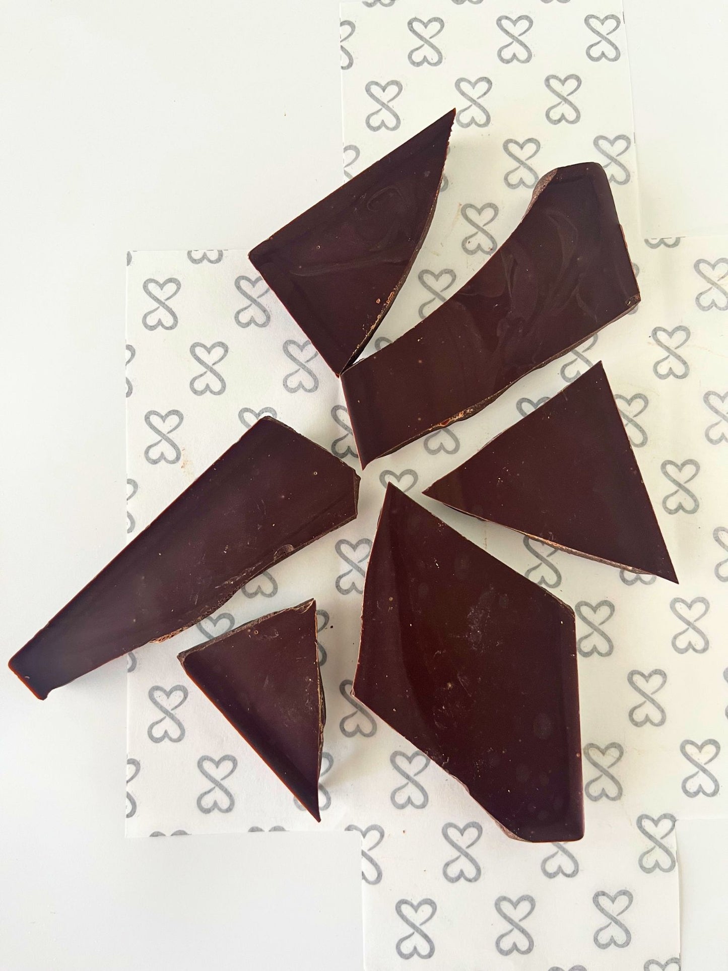 dark chocolate bar broken into pieces, on a white background