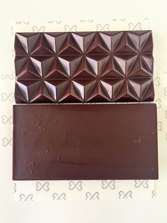 Dark chocolate bar with geometric pyramid pattern on a white background