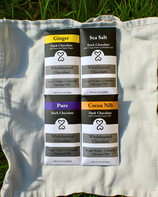 Four dark chocolate bars with different flavor labels on a white fabric background.