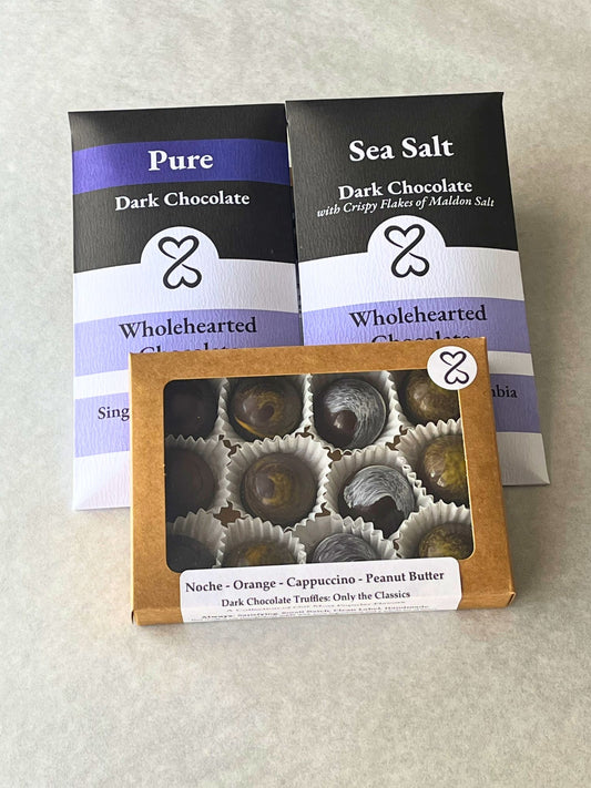 Two Wholehearted Chocolate packages, one for Pure Dark Chocolate and one for Sea Salt Dark Chocolate, with a box of truffles in front.