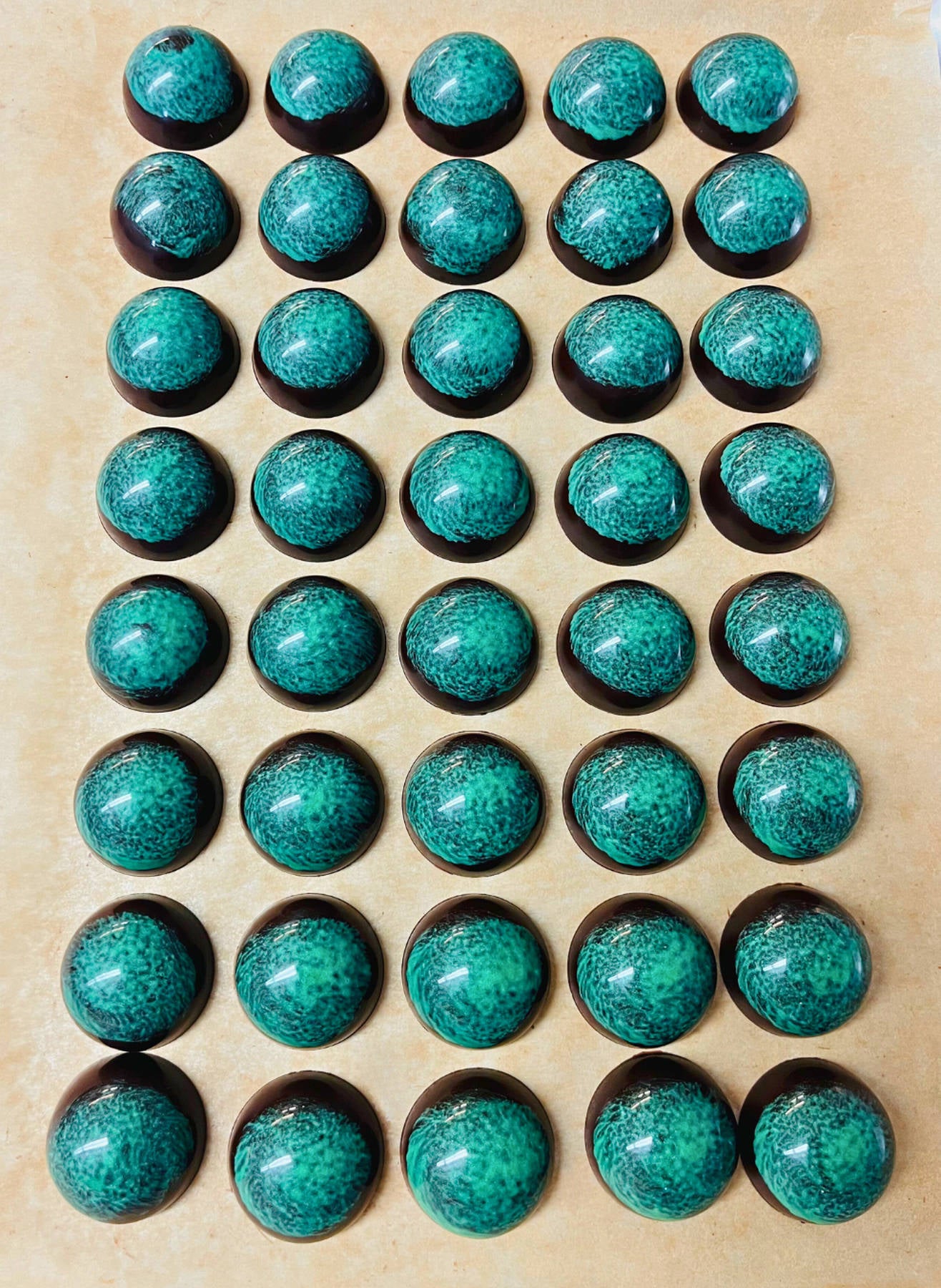 dark chocolate dome-shaped truffles with green design