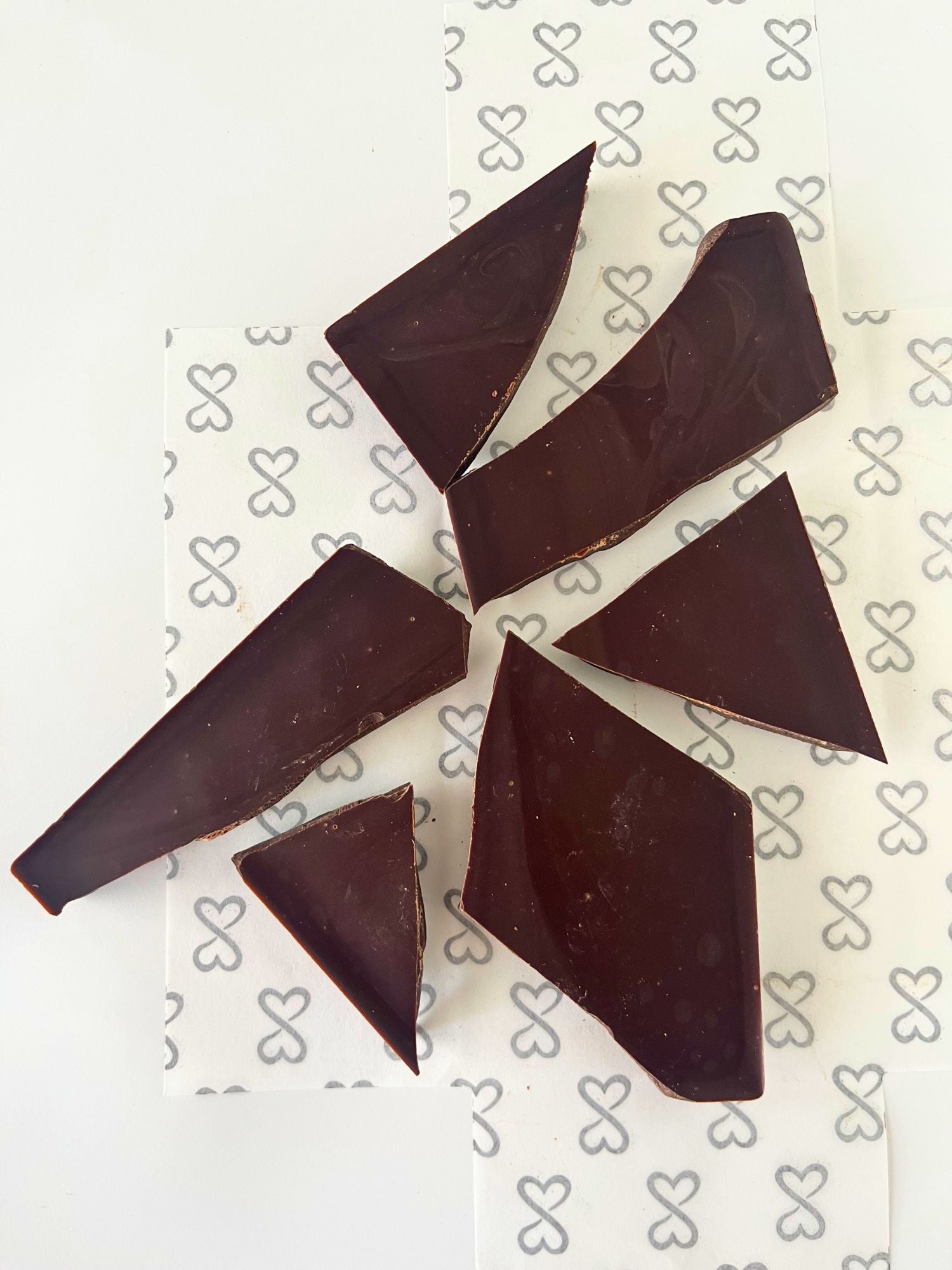 dark chocolate bar broken into pieces, on a white background