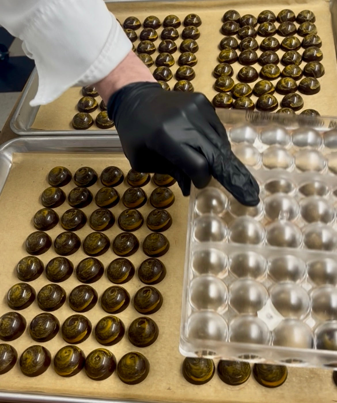 chocolatier removing orange chocolate truffles from a mold by holding it upside down
