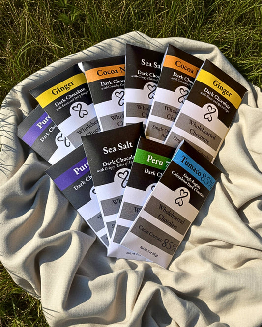 Assorted dark chocolate bars with various flavors on a blanket outdoors.
