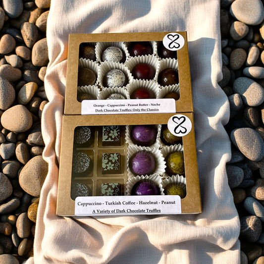 two Boxes of dark chocolate truffles on a textured fabric background with pebbles around