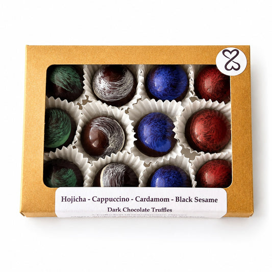 Box of dark chocolate truffles with colorful coatings on a white background