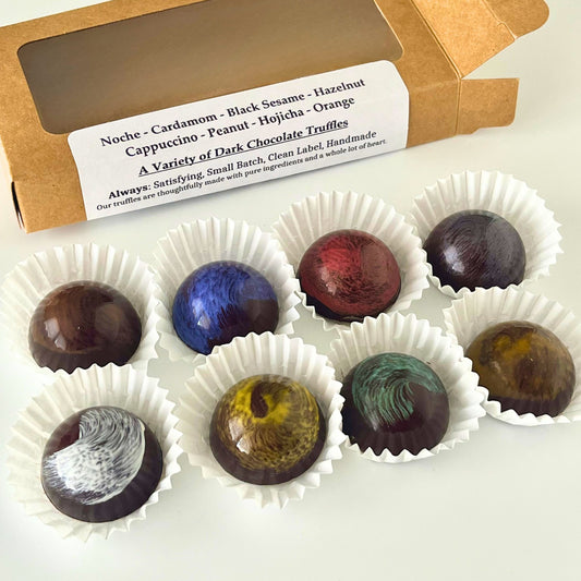 Assorted dark chocolate truffles in white paper cups with a cardboard box labeled 'A Variety of Dark Chocolate Truffles'.