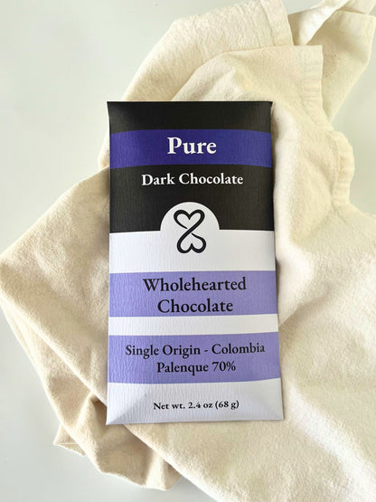 Pure Dark Chocolate bar packaging with 'Wholehearted Chocolate' branding on a beige fabric background.