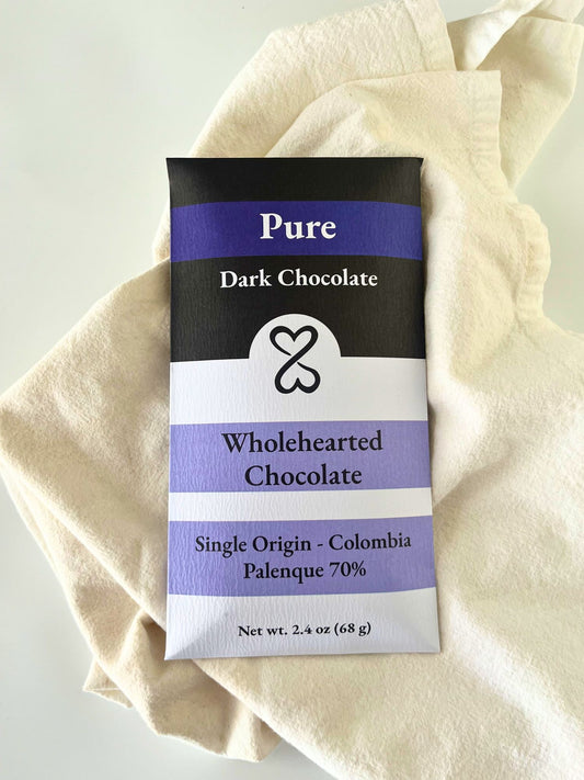 Pure Dark Chocolate bar packaging with 'Wholehearted Chocolate' branding on a beige fabric background.