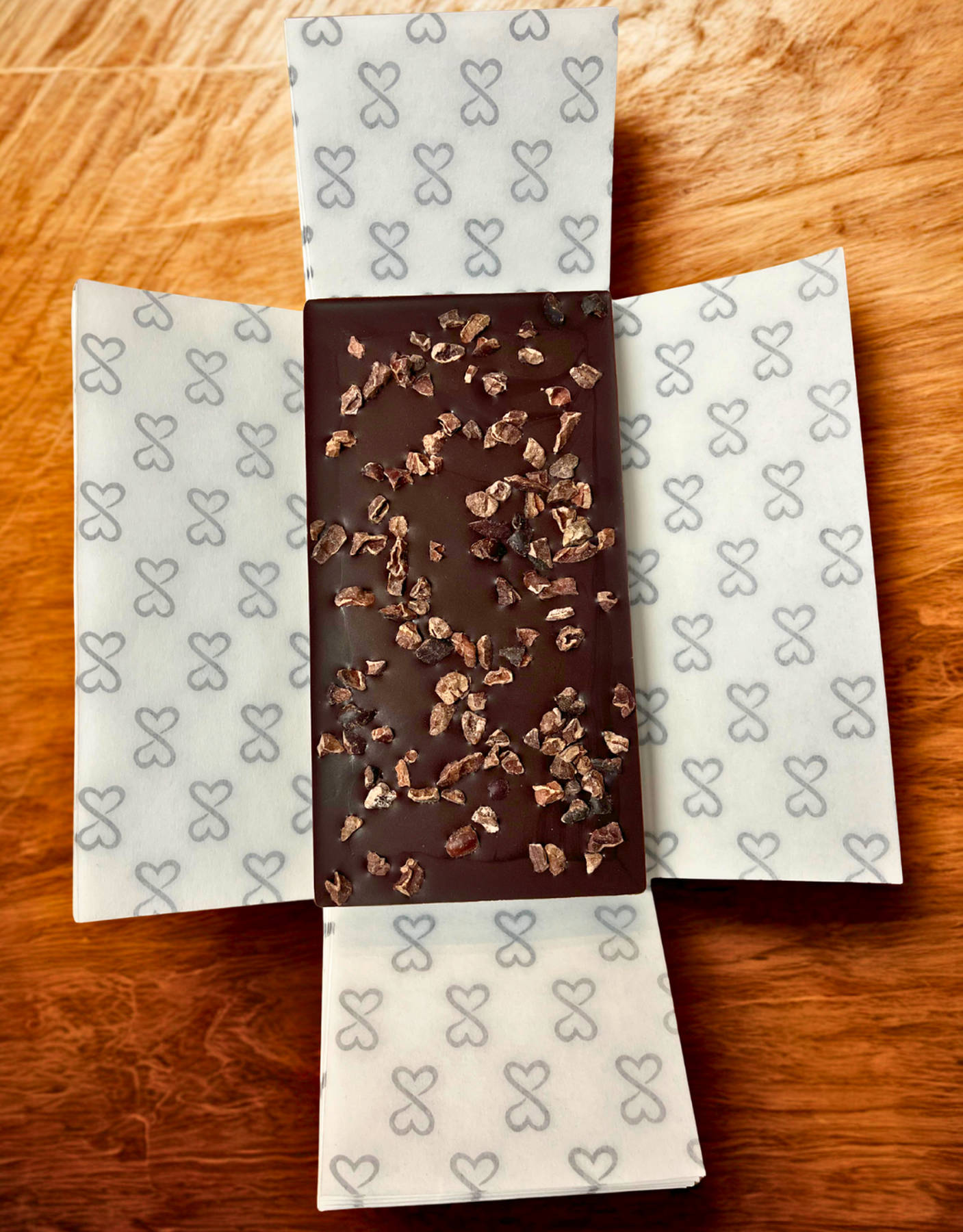 Dark chocolate bar with cacao nibs on a wooden surface