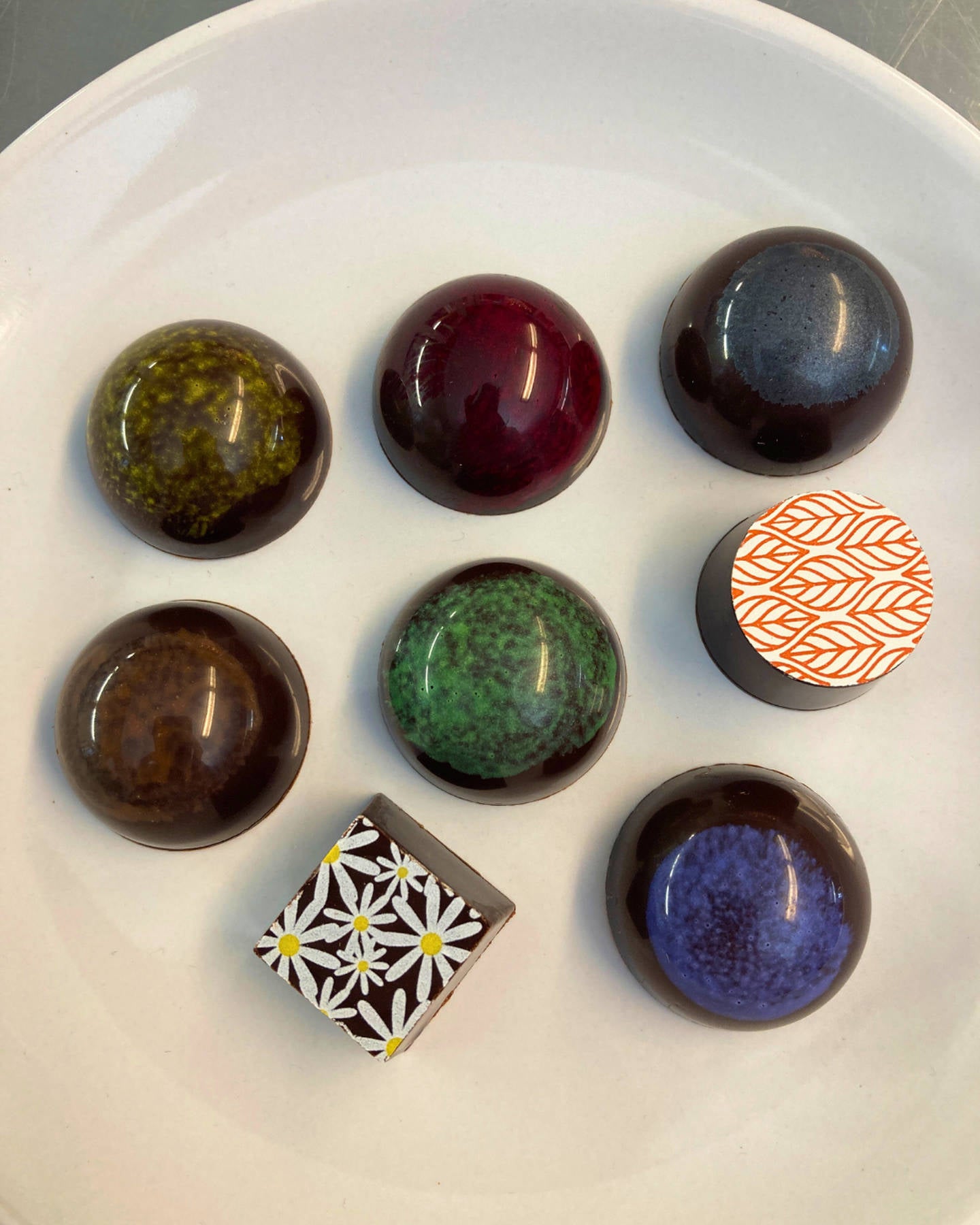 selection of colorful dark chocolate truffle and bonbon varieties. on a white plate
