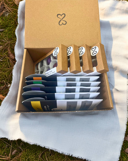 kraft box with four boxes of dark chocolates truffles and five chocolate bars inside. on a white fabric background in a natural setting