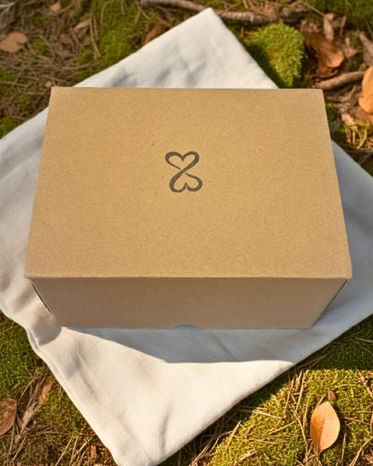 Brown kraft box with a double heart logo on a white cloth outdoors