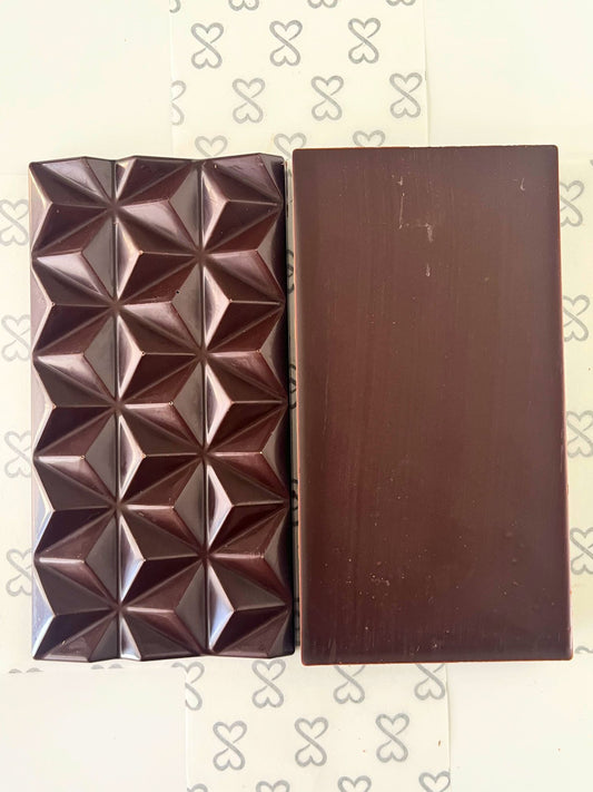 dark chocolate bar shown front and back. one side is smooth and the other has a geometric pyramid pattern