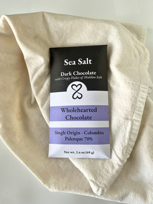 Sea Salt Dark Chocolate bar with Wholehearted Chocolate packaging on a beige cloth.