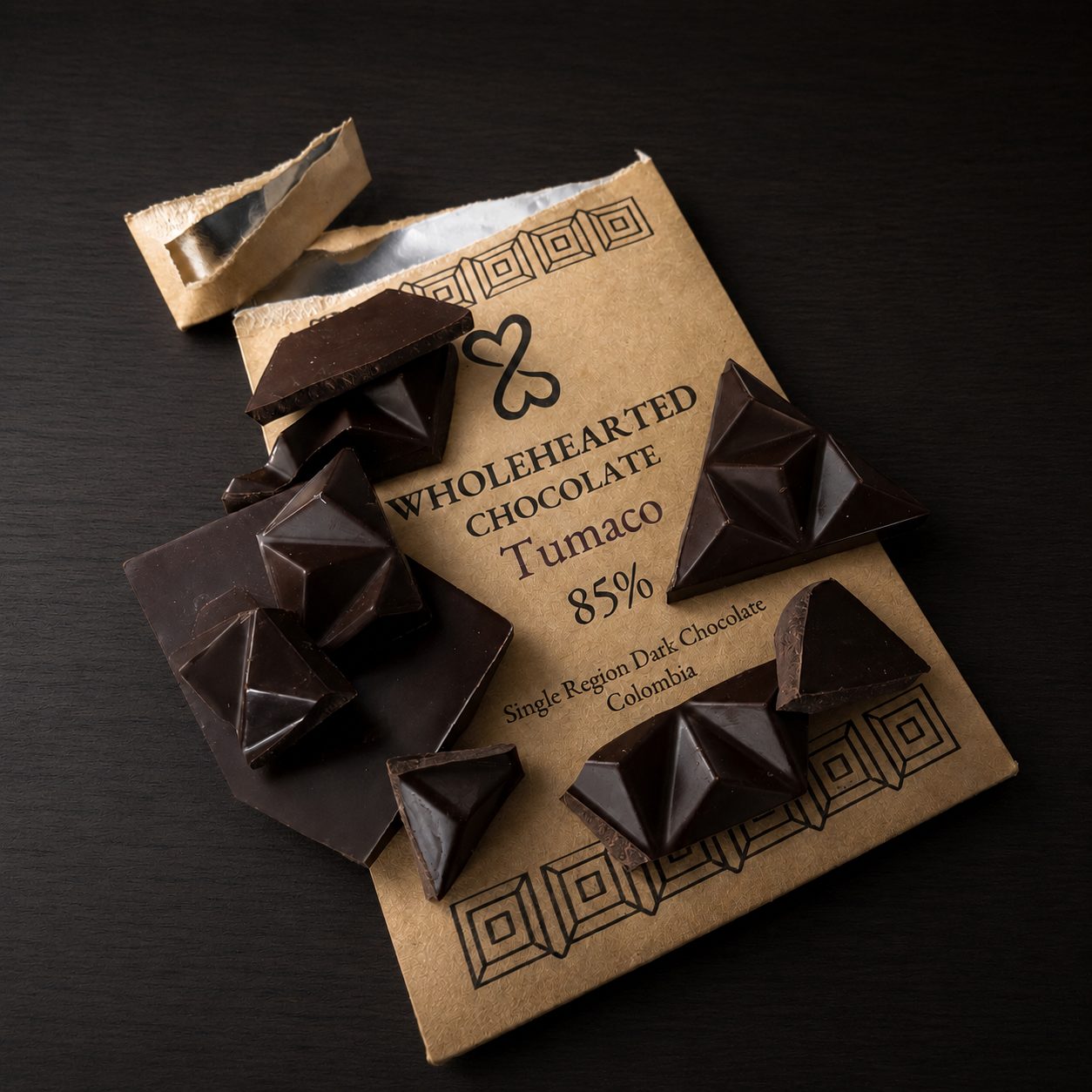 Broken Tumaco 85% dark chocolate pieces arranged over the kraft paper package