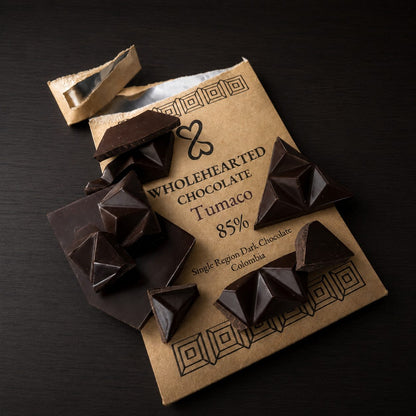 Broken Tumaco 85% dark chocolate pieces arranged over the kraft paper package